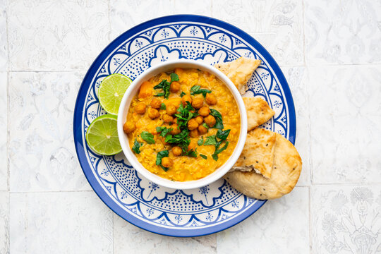 Vegan lentil curry with red lentils, sweet potatoes, spinach, roasted turmeric, chickpeas, with lime juice and coriander and naan bread
