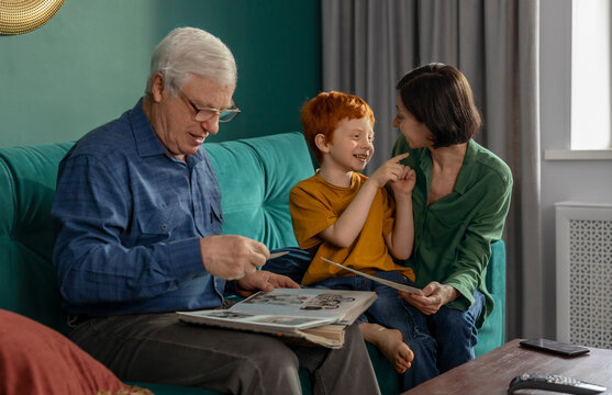 Grandfather mother and boy looking at family album at home
