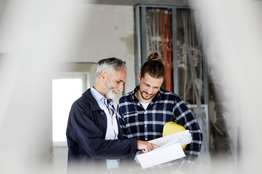 Architect explaining building plan to worker on a construction site