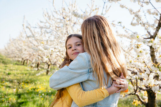 Smiling daughter hugging mother in a blooming spring garden