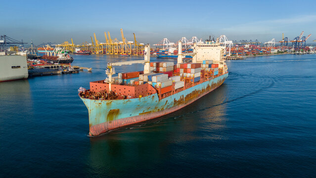 cargo container ship fully loaded transportation shipping containers navigates through the water busy commercial port terminal equipped loading cranes global maritime logistics supply chain.