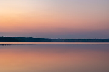 Fototapeta premium Serene pastel sunset reflection on a perfectly calm lake in Finland