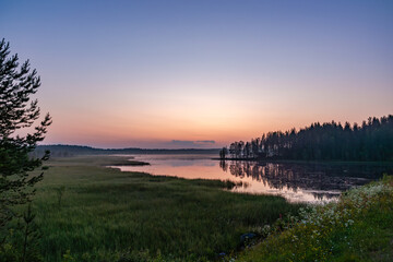 Obraz premium Serene pastel sunset reflection on a perfectly calm lake in Finland