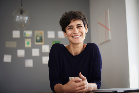 Portrait of smiling woman sitting at table at home