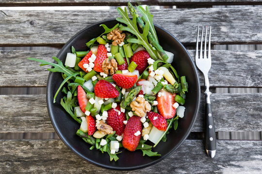 Fresh salad of asparagus, strawberries, rocket, feta cheese and walnuts