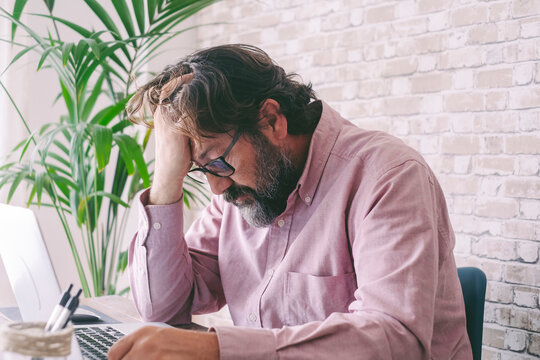 Frustrated businessman with hand in hair sitting at home
