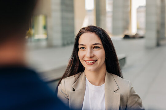 Smiling businesswoman in suit talking at outdoor interview