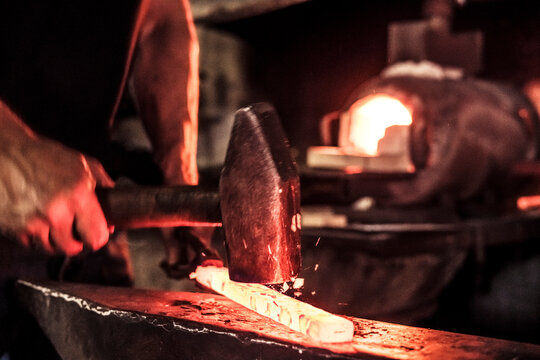 Knife maker at work, steel splinter during hammering damask steel