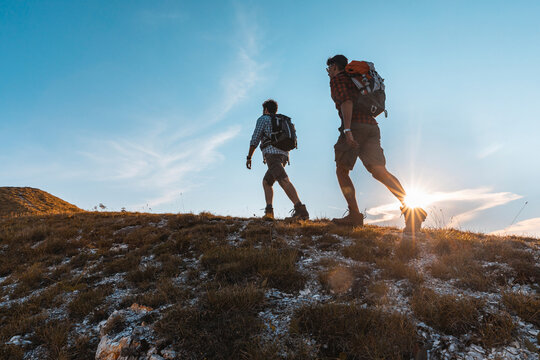 Italy, Monte Nerone, two men hiking in mountains at sunset