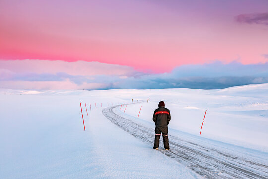 Man standing on road in winter landscape, Tana, Norway