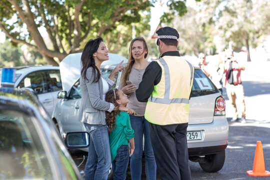 People and policeman at car accident scene