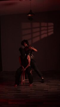 Kidnapped man with hands tied and face covered sitting on stool as armed captor enters in dramatic thriller scene