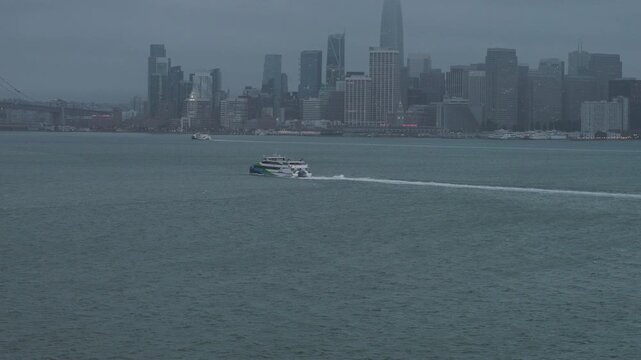 Catamaran Ferry Crossing San Francisco Bay With City Skyline And Storm Clouds