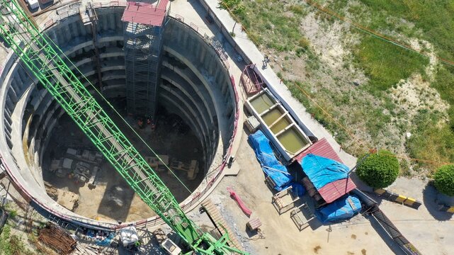 Aerial view of a deep circular construction excavation site featuring a large green crane, heavy machinery, and temporary structures in Istanbul, Istanbul, Turkiye.