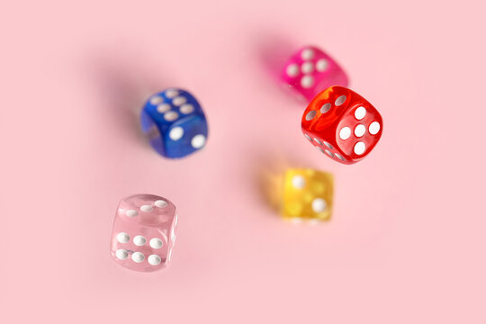 Flying colorful game dices on pink background