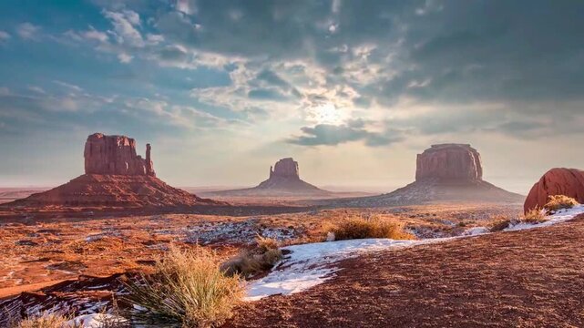 Majestic desert landscape of Monument Valley with passing clouds and winter patches of snow on the ground