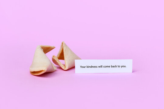 Fortune cookie with motivational text saying 'Your kindness will come back to you" on pink background