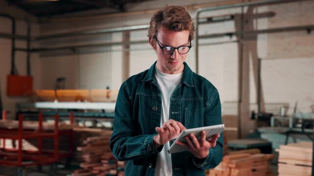 Carpentry, man and scroll on tablet in warehouse for woodwork order, design review or invoice. Timber manufacturing, carpenter and typing on tech for client email, furniture production and inventory