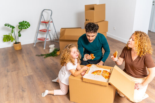 Family enjoying pizza in new home during housewarming