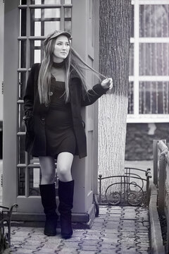 Beautiful young girl in a phone booth. The girl is talking on the phone from the payphone. English telephone booth in the street and a woman talking on phone.