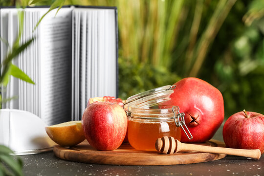 Fresh fruits, jar of sweet honey, kipa and Torah on table outdoors. Rosh hashanah (Jewish New Year) celebration