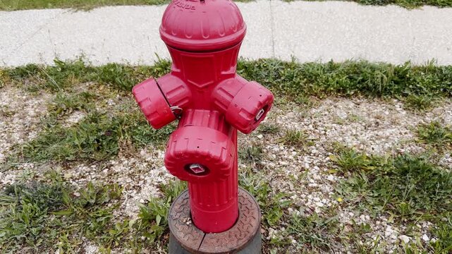 Bright red fire hydrant beside gravel, grass and a paved path, showing urban safety infrastructure in an outdoor resort or park setting.