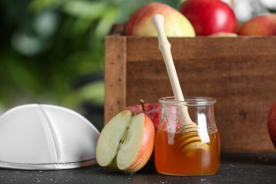 Jar of sweet honey, fresh apples and kipa on table outdoors. Rosh hashanah (Jewish New Year) celebration