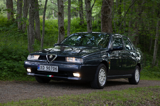 Black Alfa Romeo 155 parked on forest gravel path