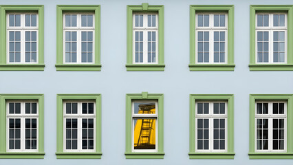 Obraz premium A close-up view of a building's facade with green window frames and a single open window showing a yellow interior