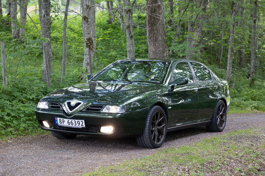 Dark reen Alfa Romeo 166 sedan rests on forest path