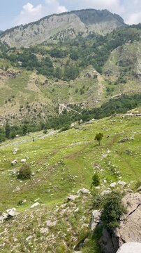 A peaceful first-person POV video of a hiker resting on a rocky mountain cliff while overlooking a breathtaking green valley. Perfect for travel, hiking, adventure, outdoor lifestyle, tourism