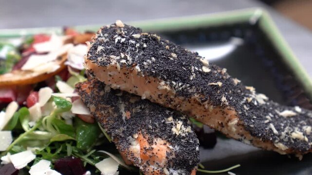 Perfectly cooked salmon crusted with poppy seeds and coconut served with a side salad