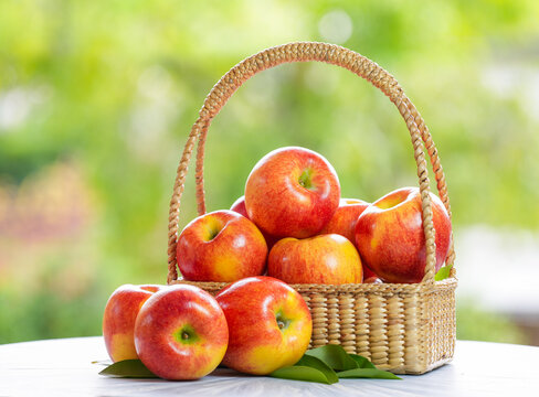 Red apple in wooden plate on wooden background, Red Envy apple over blur greenery background.