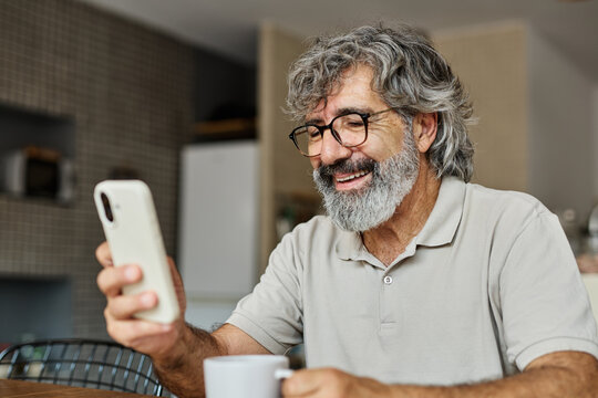 Portrait of a cheerful senior elderly man talking on phone at home