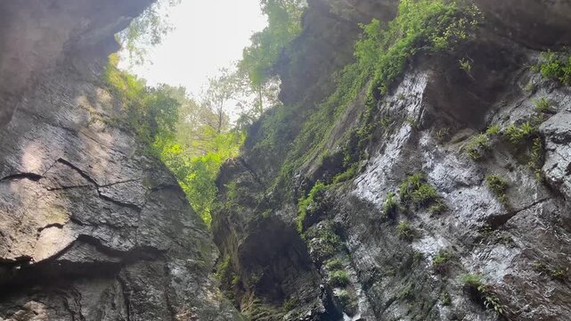 A stunning landscape video of a hidden mountain waterfall flowing through a narrow rocky gorge in Malsa, Abbottabad, Pakistan. Crystal-clear water cascades between moss-covered cliffs