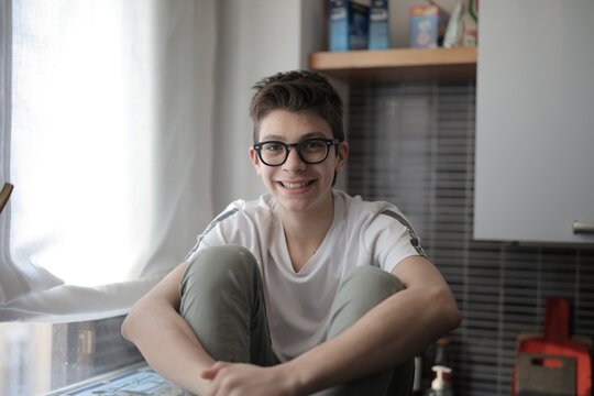 Happy teen boy wearing glasses sitting at home