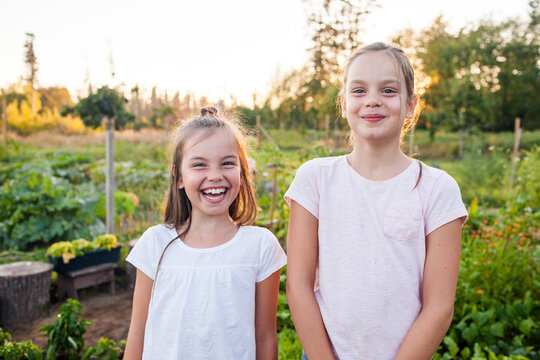 Portrait of two sisters laughing while they work in their garden