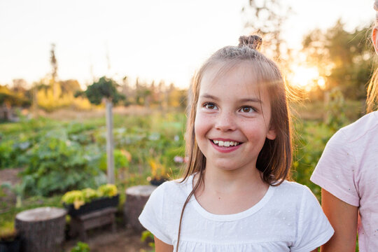 Young girl smiling outside in garden setting.