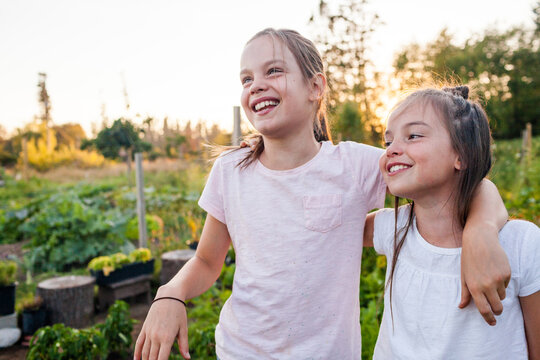 Portrait of two sisters laughing while they work outside