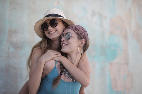 Happy young woman gives her best friend a piggyback ride
