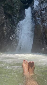 A peaceful travel and nature video featuring crystal-clear water flowing through a hidden mountain waterfall surrounded by rugged rocks and lush greenery. 