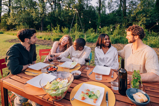Diverse friends enjoying outdoor dinner party laughing together