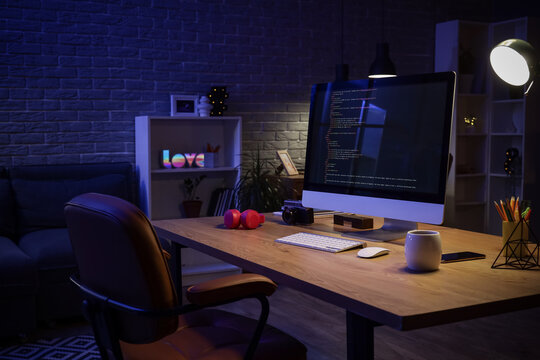 Programmers desk with computer and coffee cup in office at night