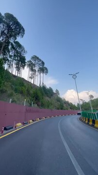 A smooth vertical driving video captured on the scenic Murree Expressway in Pakistan. Featuring a winding mountain road, lush green pine forests, modern streetlights, and a peaceful travel atmosphere.