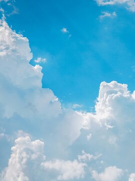 Vibrant vertical view of fluffy white cumulus clouds in bright blue sky evoking freedom inspiration and natural background for corporate advertising.