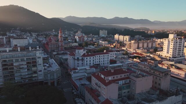 Drone Aerial view of dense city skyline with mountain backdrop at sunrise