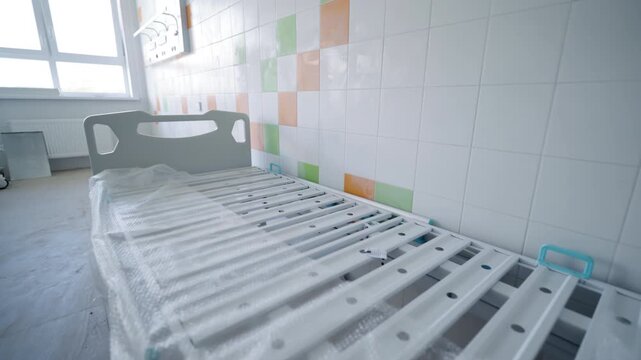 New medical bed stands in freshly renovated hospital ward. Cheerful orange and green ceramic tiles bring pleasant welcoming energy