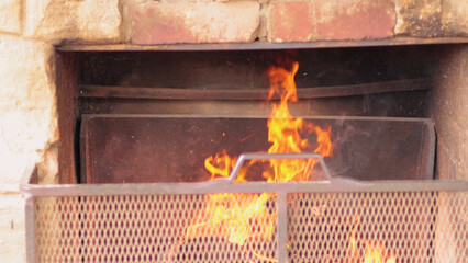 Fototapeta premium Warm Flames Flickering Inside a Rustic Stone and Brick Fireplace