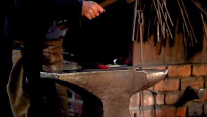 Blacksmith Forging Glowing Red Metal on an Anvil in a Workshop © blueringmedia
