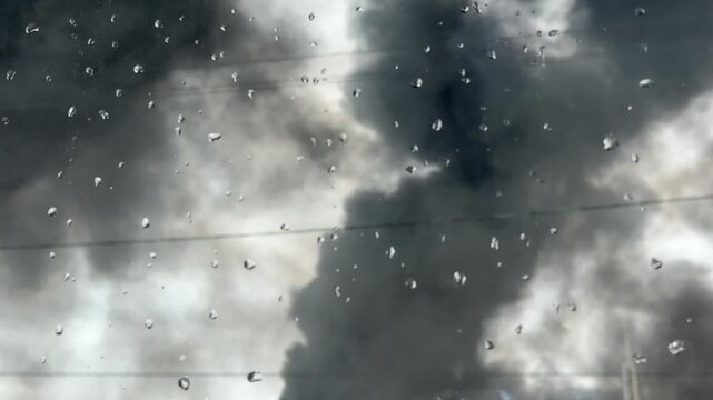 Rain, glass, window, view of stormy dark clouds through a water droplet covered pane on a gloomy autumn day after the rain